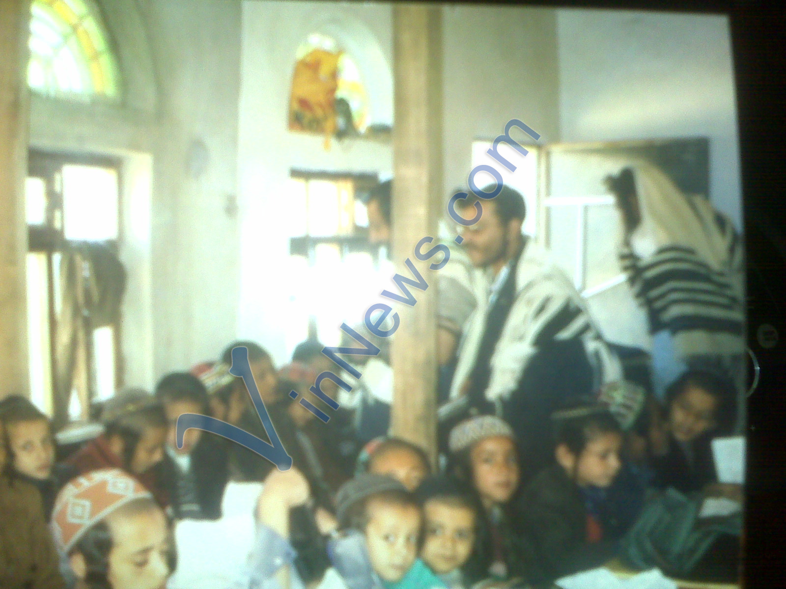 Mosha seen in Talis and Tefilin praying in Shul with his Talmidim