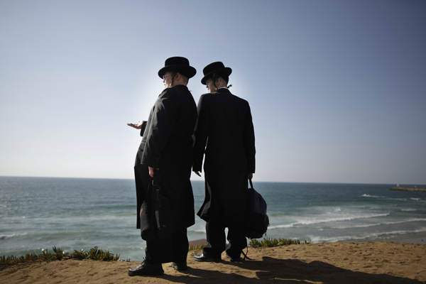  In this picture taken Wednesday, Aug. 12, 2009, two Ultra-Orthodox Jewish men stand on a segregated beach in Herzliya, north of Tel Aviv. During the summer months religious Jews have a section of the beach in Herzliya that is reserved for them. The beach is segregated so that on alternating days it is only men or women. (AP Photo/Ariel Schalit) Ariel Schalit