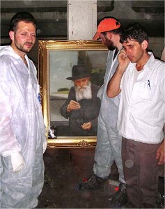 Jewish volunteers stand around a portrait of the Lubavitcher Rebbe, Rabbi Menachem Mendel Schneerson, amidst the ruined Beit Chabad in Mumbai. The Picture of the Rebbe unscathed in attack