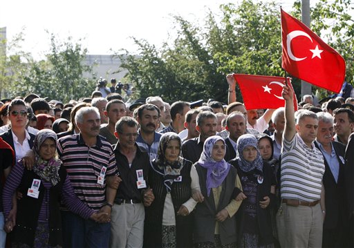 Family members hold national flags during a funeral ceremony for Huseyin Koksal, photo, one of eleven Turkish soldiers killed Saturday by Kurdish rebels of the Kurdistan Workers Party, or PKK, in Ankara, Turkey, Sunday, June 20, 2010. Turkey's prime minister and military commanders traveled to the country's border with Iraq to assess security on Sunday and vowed that Kurdish rebels who killed 12 Turkish soldiers over the weekend in cross-border attacks will "drown in their own blood."  Kurdish rebels have dramatically stepped up attacks in Turkey in recent months, threatening a government attempt to end one of the world's longest guerrilla wars.(AP Photo/Burhan Ozbilici)