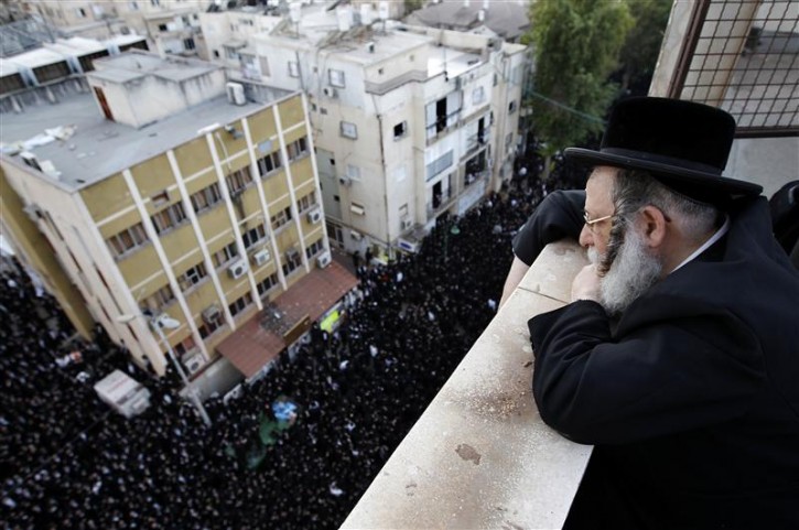 An Ultra-Orthodox Jewish man looks at the burial ceremony in Bnei Brak near Tel Aviv for Torah scrolls that were destroyed in a fire, October 7, 2010. Eleven torah scrolls were damaged in a fire that broke out in a synagogue during the Jewish holiday of Sukkot following a short circuit in the Holy Ark. REUTERS/Ronen Zvulun