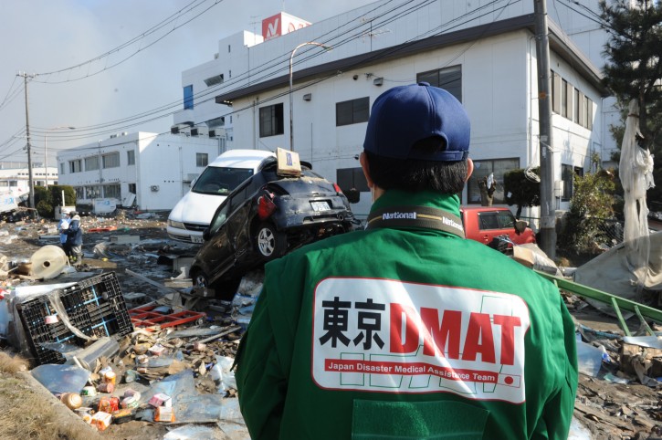 A 'Japan Disaster Medical Assistance Team' member looks at the scene of devastion at Sendai Port 13 March 2011 after an earthquake and tsunami  ravaged much of Japan's Pacific East coast on 11 March 2011. Japanese police say that the number of people killed in the disaster could surpass 10,000  EPA/ALEX HOFFORD