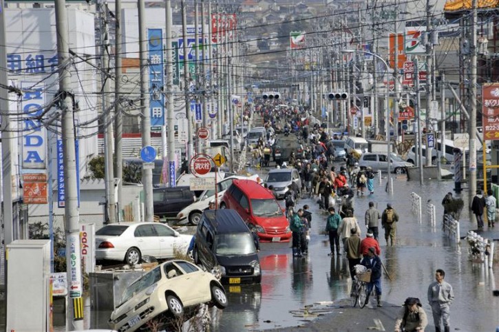 People walk along a flooded street in Ishimaki City, Miyagi Prefecture in northern Japan, after an earthquake and tsunami struck the area, March 13, 2011. REUTERS/Kyodo