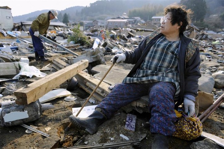 A woman looks out over the destroyed landscape in Ofunato City, Iwate Prefecture in northern Japan, after an earthquake and tsunami struck the area, March 13, 2011. Japan faces a growing humanitarian crisis on a scale not seen since World War Two after its devastating earthquake and tsunami left millions of people without water, electricity, homes or heat.  REUTERS/Kyodo 