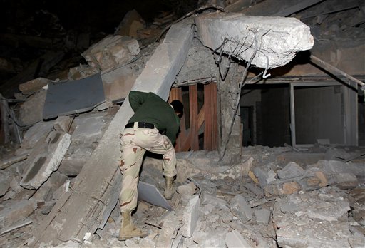 A Libyan soldier surveys the damage to an administrative building hit by a missile late Sunday, March 20, 2011 in the heart of Moammar Gadhafi's Bab Al Azizia compound in Tripoli, Libya, as he is pictured during an organized trip by the Libyan authorities. No casualties were reported. (AP Photo/Jerome Delay)