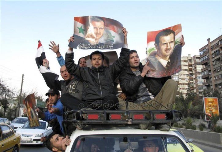 Supporters of Syria's President Bashar al-Assad shout slogans as they hold up his pictures from atop a car in Damascus March 25, 2011. Protests spread across Syria on Friday, challenging the rule of the Assad family after their forces killed dozens of demonstrators in the south.    REUTERS/Thaier al-Sudani 