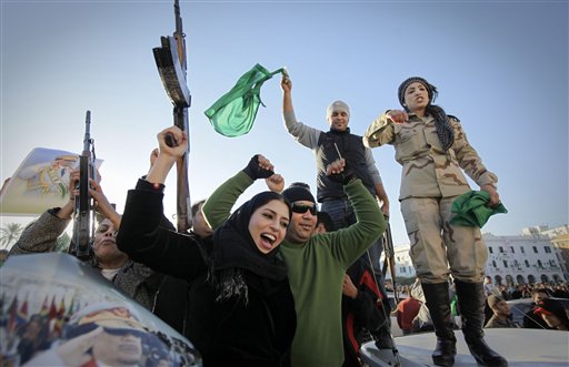 The female relative of a fighter, center, holds her weapon in the air, as pro-Gadhafi soldiers and supporters gather to celebrate in Green Square,  Tripoli, Libya Sunday, March 6, 2011. Thousands of Moammar Gadhafi's supporters poured into the streets of Tripoli on Sunday morning, waving flags and firing their guns in the air in the Libyan leader's main stronghold, claiming overnight military successes. (AP Photo/Ben Curtis)