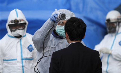 An official scans a man for radiation at an emergency center Sunday, March 13, 2011, in Koriyama, northeastern Japan, two days after a giant quake and tsunami struck the country's northeastern coast.(AP Photo/Gregory Bull)