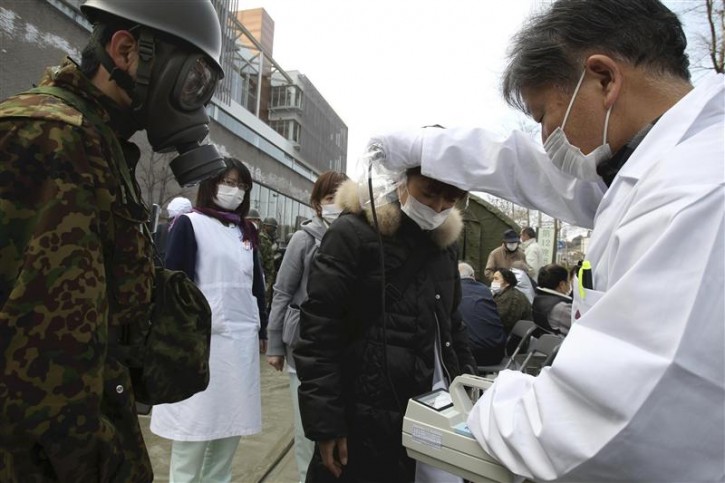 An official scans for signs of radiation on a woman in Nihonmatsu City in Fukushima Prefecture March 13, 2011 after radiation leaked from an earthquake-damaged Fukushima Daini nuclear reactor. Japan battled to contain a radiation leak at an earthquake-crippled nuclear plant on Sunday, but faced a fresh threat with the failure of the cooling system in a second reactor.  REUTERS/Yomiuri Shimbun