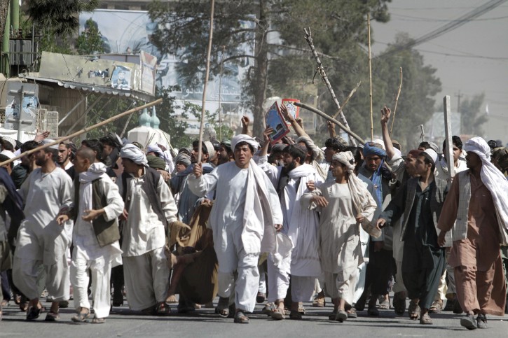 Afghan protestors walk with sticks, as they carry a wounded colleague during a demonstration to condemn the burning of a copy of the Muslim holy book by a U.S. Florida pastor, in Kandahar southern of Afghanistan on Saturday, April. 2, 2011. The governor's office in Kandahar has raised the death toll to nine in a Quran burning protest that turned violent in southern Afghanistan. (AP Photo/Allauddin Khan)