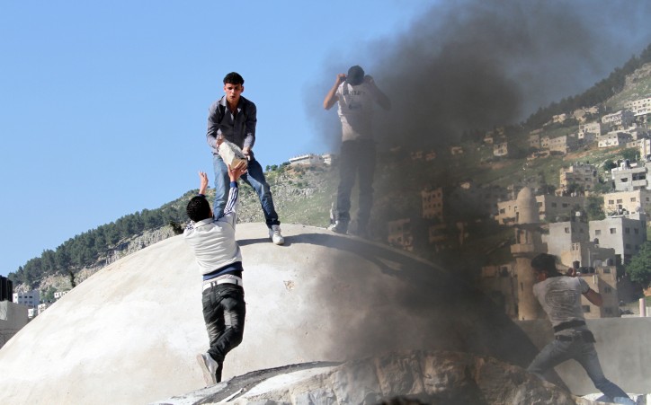 Palestinian youths burn tyres at the entrance to the shrine of Joseph's Tomb in the West Bank city of Nablus, 24 April 2011.EPA 