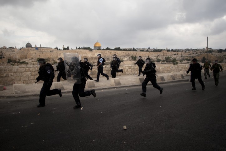 Backdropped by the dome of the rock, Israeli police officers run as Palestinian protesters, not seen, hurl stones after the funeral of Palestinian Milad Said Ayyash, 17, who died of wounds sustained in yesterday's protests near the east Jerusalem neighborhood of Silwan in east Jerusalem Saturday, May 14, 2011. (AP Photo/Sebastian Scheiner)