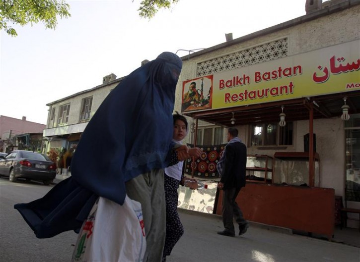 An Afghan woman clad in burqa and her daughter walks past a restaurant built inside part of the only synagogue building in Kabul, June 1, 2011. A lattice of iron Star of David marks Afghanistan's only working synagogue, a white-washed, two-storey building tucked into a side street in the centre of Kabul. REUTERS/Omar Sobhani 