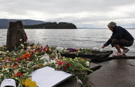 A woman lights a candle in Sundvollen, facing Utoya island, where gunman Anders Behring Breivik killed at least 68 people, near Oslo, Norway, Tuesday, July 26, 2011. AP