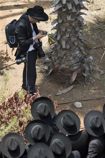 In this photo taken Tuesday, June 28, 2011, an ultra-Orthodox Jewish photojournalist uses a mobile phone during the funeral of Rabbi Michel Yehuda Lefkowitz, Lithuanian-Orthodox leader, head of the Ponevezh yeshiva, in Bnei Brak, Israel. The community of ultra-Orthodox Jews in Israel, long an insular island where rabbis ruled and the outside world was viewed with suspicion or ignored altogether, is being quietly and profoundly altered by a proliferation of new media outlets shining a light on topics that were long taboo. (AP Photo/Ariel Schalit)