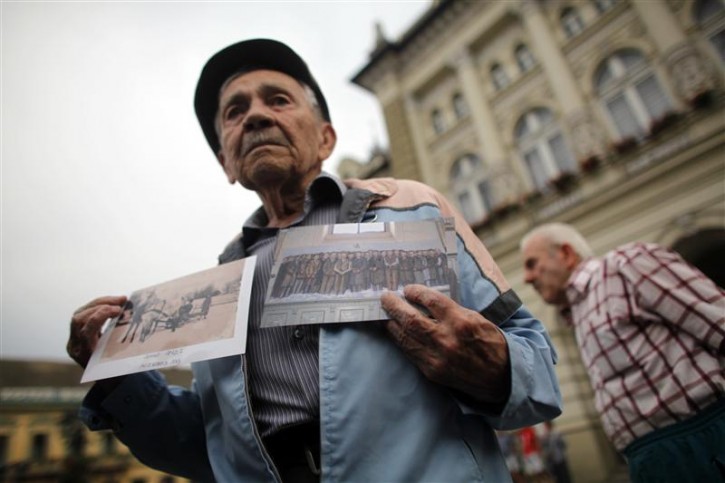 Ljubisa Lekic, an eyewitness of the January 1942 massacre, holds pictures during a rally against the acquittal of Sandor Kepiro, former WW2 Hungarian gendarme and a war crimes suspect in Novi Sad July 24, 2011. Earlier in July, Hungarian court cleared the 97-year-old former gendarme officer from charges of taking part in a mass killing of Serbs, Jews and Roma in January 1942.  REUTERS/Marko Djurica 