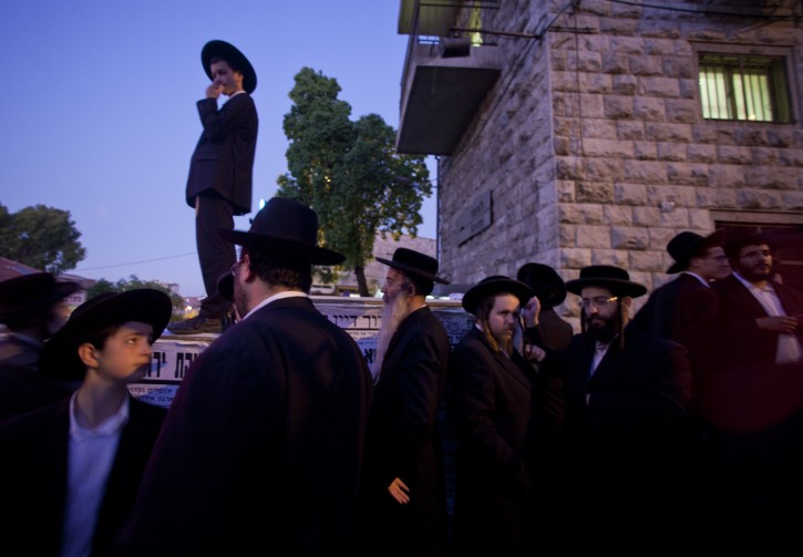 A teenage ultra-Orthodox Jew stands atop a wall as he and joins a protest of several thousand Hassidic Jews gathered in Sabbath Square in the Mea Shearim neighborhood in Jerusalem on 11 August 2011 protesting against social events planned for the summer by the Jerusalem municipality, which the religious community claims will break the Sabbath laws of Judaism, and corrupt religious people.  EPA/JIM HOLLANDER