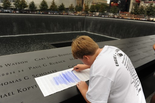 FILE - In this Sept. 11, 2011 file photo, August Larsen, 9, makes a crayon rubbing of the name of his father, Scott Larsen, engraved on the bronze parapet overlooking the south pool of at the National September 11 Memorial in New York on the 10th anniversary of the attacks on the World Trade Center. Scott Larsen, a firefighter at Ladder 15, never met his son, who was born just a few days after Scott's death in the terrorist attacks. The memorial, placed in the footprints of the twin towers, was designed with the rubbings in mind. (AP Photo/Aaron Showalter, Pool, File)