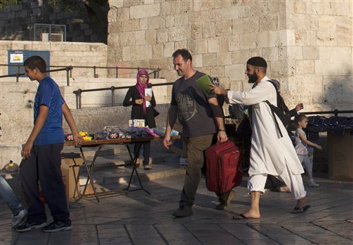 In this Tuesday, Sept. 27, 2011 photo, a Muslim missionary approaches a passer by with a pamphlet about Islam outside Damascus Gate in Jerusalem's Old City.  In an unprecedented endeavor, a small number of Muslim believers are crossing the Holy Land's volatile boundaries of culture, faith and politics to bring Islam to their Jewish neighbors and adversaries, hoping, improbably, that some will be willing to renounce their religion for a new one. There are no signs that the endeavor has met with any success. But the act of spreading Islam in Hebrew is profound, reflecting a striking confidence on the part of some Muslims, members of Israel's one-fifth strong Arab minority, who are intimately familiar with its people, laws and language.(AP Photo/Dusan Vranic)