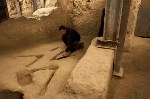 Eli Shukron, an archaeologist with Israel's Antiquities Authority, sweeps marks carved in the bedrock in an archaeological excavation in the City of David, near Jerusalem's Old City.AP