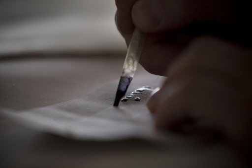 In this Tuesday, Jan. 17 2012 photo, calligraphy expert Avraham Borshevsky practices at his studio in Jerusalem. Parchment, feathers and "qalams," a pen made of dried bamboo, are still used by sophers Jewish scribes and khattats Muslim calligraphers. (AP Photo/Bernat Armangue)