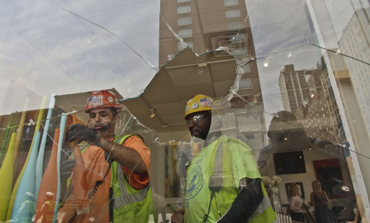 Construction workers remove window display items near the shattered window of Kolb Art Gallery following damage from an intentional underground explosion on the Second Avenue subway project on East 72nd on Tuesday, Aug. 21, 2012.  (AP Photo/Bebeto Matthews)