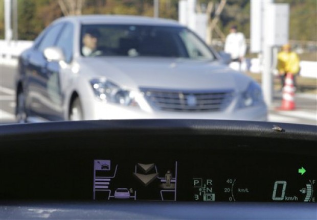 A human sign and an arrow pop up on a dashboard display to notify the driver of a pedestrian's presence and an approaching car at the coming intersection during a demonstration of Toyota Motor Corp.'s Intelligent Transport System at its Higashi-Fuji Technical Center in Susono, southwest of Tokyo, Monday, Nov. 12, 2012. (AP Photo/Koji Sasahara)