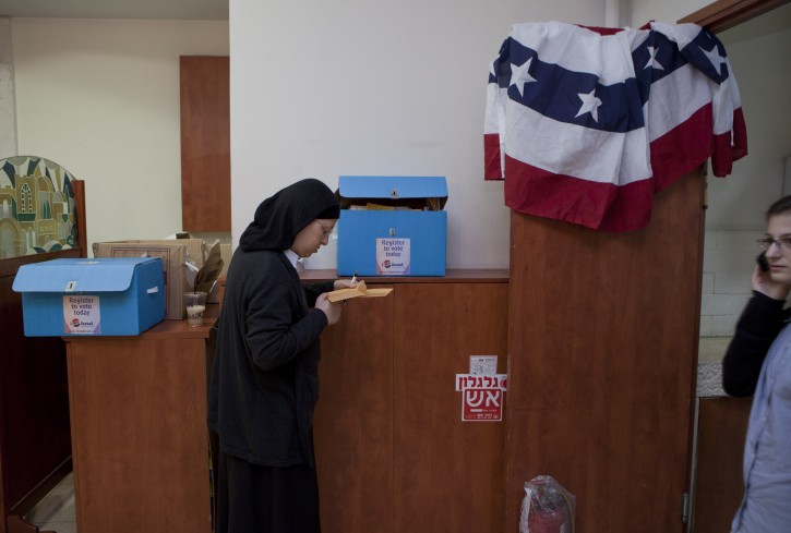 A religious American Jewish woman completes her forms next to ballot boxes and an American banner as American nationals in Israel cast their vote in the USA presidential elections, in Jerusalem, Israel, 23 October 2012. EPA/JIM HOLLANDER