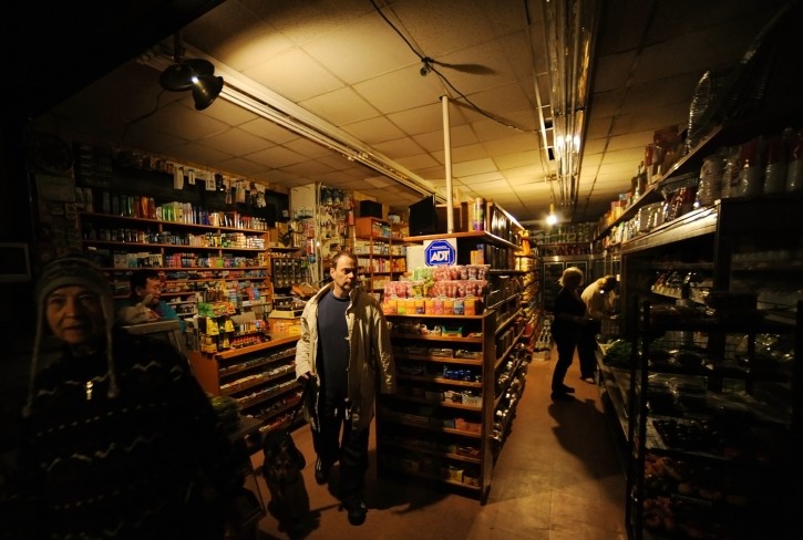People shop in a grocery store with lights from a portable generator on Bleeker Street in New York City, New York, USA, 31 October 2012. EPA/PETER FOLEY