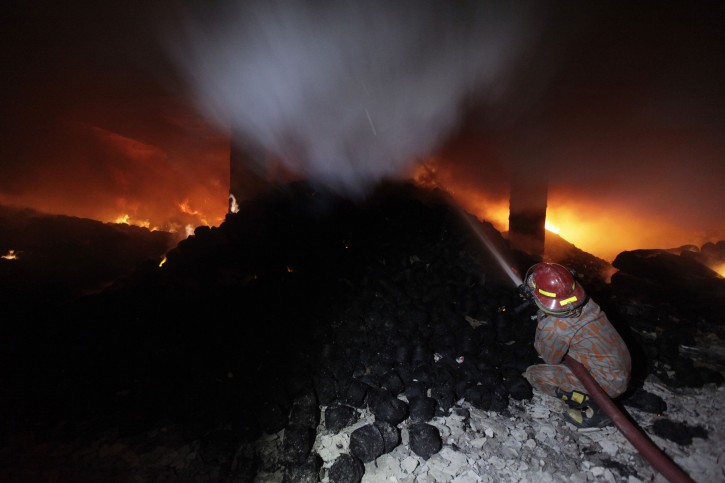 A firefighter tries to control a fire at a garment factory in Savar, outskirts of Dhaka November 24, 2012. At least 120 died and over 100 were injured as a fire broke out at Tazreen Fashions Limited in Savar on Saturday evening, police said.  REUTERS/Andrew Biraj 