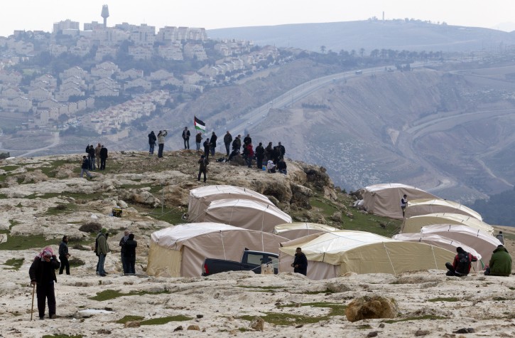 A Bedouin man (L) leaving what Palestinians call the new 'outpost settlement' of Bab al-Shams (Gate of the Sun), 11 January 2013, set-up outside the Palestinian West Bank village of Ez Za'im in the contentious area east of Jerusalem, in the West Bank known as E1, overlooking the sprawling Jewish settlement of Ma'ale Adumim, partially seen behind. EPA/JIM HOLLANDER