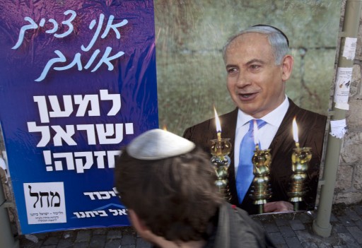 An observant Jewish young man looks at an election poster showing IsraeliPrime Minister Benjamin Netanyahu, leader of the Likud - Yisrael Beitenu joint party, as he lights Chanukkah candles and wears a Yamulka, or Jewish skullcap, under the banner in Hebrew that reads, 'I Need You For A Strong Israel,' in Jerusalem, 15 January 2013. EPA/JIM HOLLANDER
