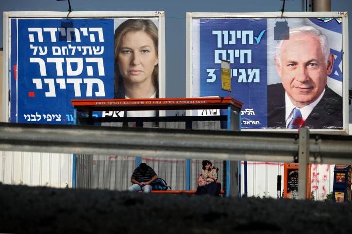 People wait at a bus stop near billboards of Benjamin Netanyahu (R) and Tzipi Livni (L), in Tel Aviv, Israel, 20 January 2013. EPA/ABIR SULTAN