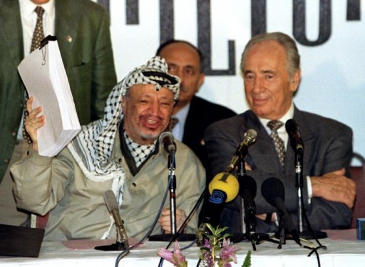 FILE - PLO chairman Yasser Arafat holds the second phase of the Oslo peace accords after the initialling of the document, September 24 1995, as Israeli Foreign Minister Shimon Peres looks on. REUTERS
