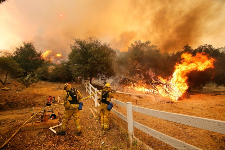 Ffirefighters from Stockton, Calif.,  put out flames off of Hidden Valley Rd. while fighting a wildfire, Friday, May 3, 2013 in Hidden Valley, Calif. A huge Southern California wildfire burned through coastal wilderness to the beach on Friday then stormed back through canyons toward inland neighborhoods when winds reversed direction. (AP Photo/Los Angeles Times, Mel Melcon) 