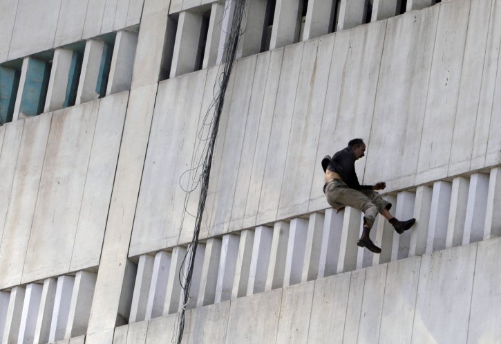 A man jumps from a building that caught on fire in Lahore, Pakistan, Thursday, May 9, 2013. The 13-storey government building caught fire and quickly intensified spreading to three floors of the tall building. (AP Photo/K.M. Chaudary)