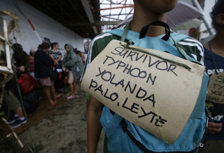 Typhoon survivors hang signs from their necks as they queue up in the hopes of boarding a C-130 military transport plane Tuesday, Nov. 12, 2013, in Tacloban, central Philippines. Thousands of typhoon survivors swarmed the airport on Tuesday seeking a flight out, but only a few hundred made it, leaving behind a shattered, rain-lashed city short of food and water and littered with countless bodies. The typhoon, known as Haiyan elsewhere in Asia but called Yolanda in the Philippines, was likely the deadliest natural disaster to beset this poor Southeast Asian nation. (AP Photo/Bullit Marquez)