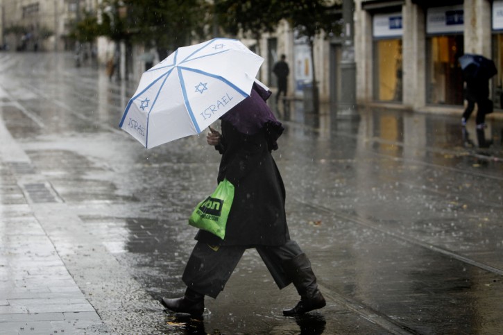 A woman holds an umbrella to protect herself from the rain as she crosses Jaffo Street, on a winter day in the center of Jerusalem. December 11, 2013. Photo  by Miriam Alster/FLASH90 