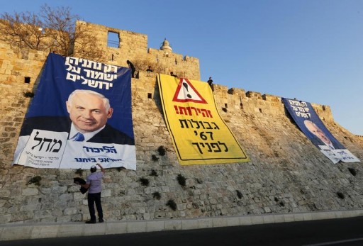 A man stands next to campaign banners depicting Israel's Prime Minister Benjamin Netanyahu after Likud-Yisrael Beitenu activists draped them on walls surrounding Jerusalem's Old City January 20, 2013.Reuters 