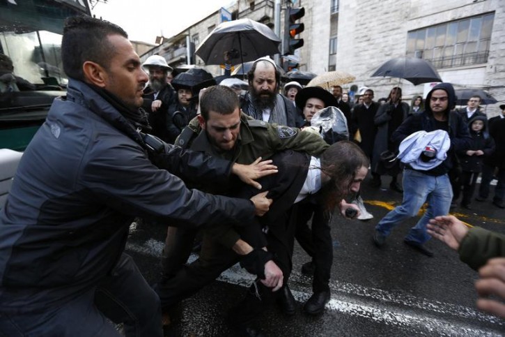 An ultra-Orthodox Jewish protester is detained by an Israeli policemen during clashes in Jerusalem's Mea Shearim neighbourhood December 5, 2013. An Israeli police spokesperson said on Thursday two ultra-Orthodox Jewish protesters were detained during clashes with police at a protest against the jailing of a Jewish seminary student in a military prison after he failed to comply to a recruitment notice he was sent. REUTERS/Baz Ratner