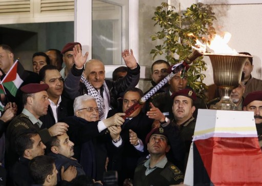 Palestinian President Mahmoud Abbas (C) lights a fire with a torch as he welcomes Palestinian prisoners released from Israeli prisons, in the West Bank city of Ramallah early December 31, 2013. Reuters