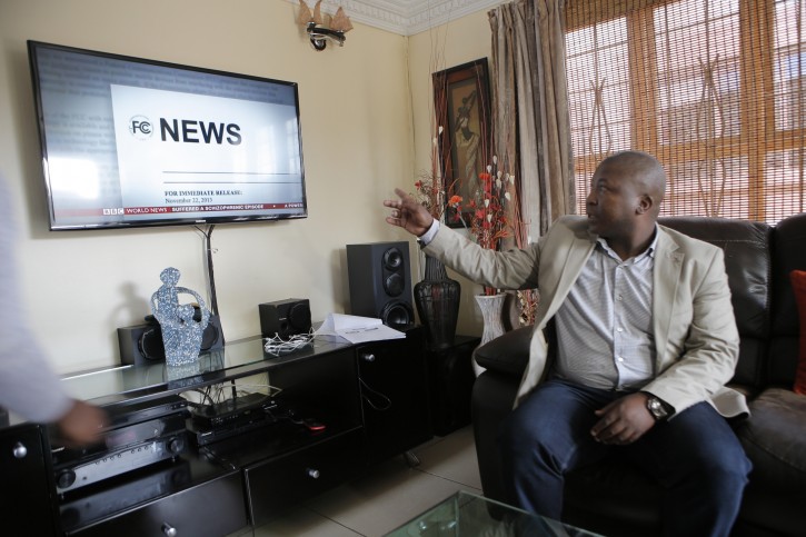 Thamsanqa Jantjie looks around at a television at his home during an interview with the Associated Press in Johannesburg, South Africa,Thursday, Dec. 12, 2013. Jantjie, the man accused of faking sign interpretation next to world leaders at Nelson Mandela's memorial, told a local newspaper that he was hallucinating and hearing voices. (AP Photo/Tsvangirayi Mukwazhi)