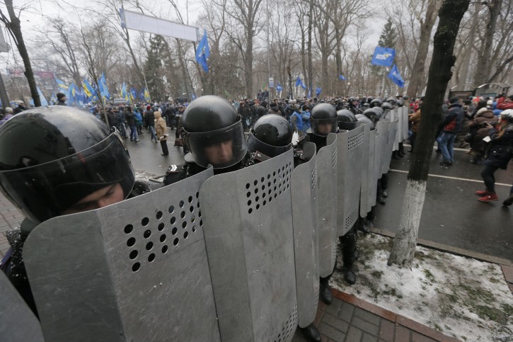 Riot police protect government buildings from the Pro-European Union activists, pro-Presidential supporters behind them,  in  Kiev, Ukraine, Sunday, Dec. 8, 2013. The third week of protests continue Sunday with an estimated 200,000 Ukrainians occupying central Kiev to denounce President Viktor Yanukovychs decision to turn away from Europe and align this ex-Soviet republic with Russia. (AP Photo/Efrem Lukatsky)