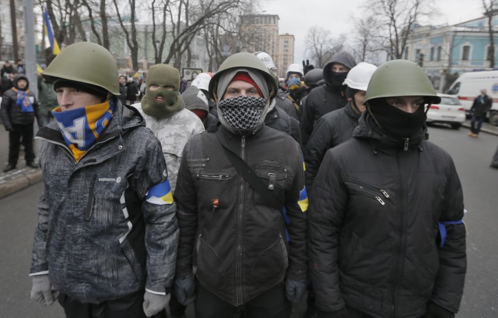 Pro-European Union activists  in military helmets march along streets to block government offices in Kiev, Ukraine, Sunday, Dec. 8, 2013. The third week of protests continue Sunday with an estimated 200,000 Ukrainians occupying central Kiev to denounce President Viktor Yanukovychs decision to turn away from Europe and align this ex-Soviet republic with Russia. (AP Photo/Efrem Lukatsky)