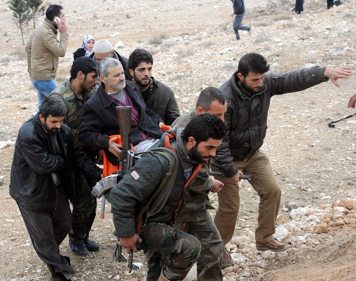 A handout picture made available on 30 December 2013 by the Syrian Arab News Agency SANA, shows the surviving residents of the industrial city of Adra, northeast of Damascus, helping an elderly man, during an evacuation operation by the Syrian army soldiers.