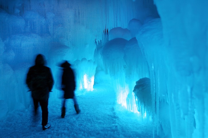 In this Wednesday, Jan. 8, 2014 photo, patrons tour an ice castle at the base of the Loon Mountain ski resort in Lincoln, N.H. The ice castle begins to grow in the fall when the weather gets below freezing and thousands of icicles are made and harvested then placed around sprinkler heads and sprayed with water. The castle will continue to grow as long as the temperatures stay below freezing. (AP Photo/Jim Cole)
