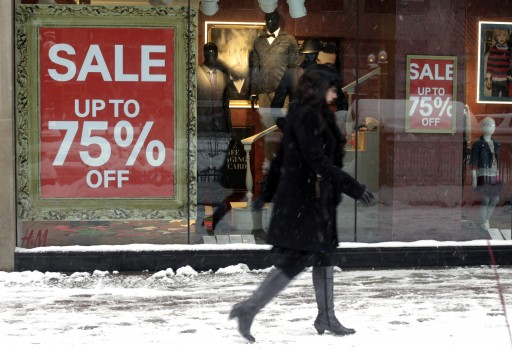 In this Jan 2, 2014 photo, a pedestrian passes by sale signs on a store front window in Chicago. The Conference Board releases the Consumer Confidence Index for January, on Tuesday, Jan. 28, 2014. (AP Photo/Kiichiro Sato)