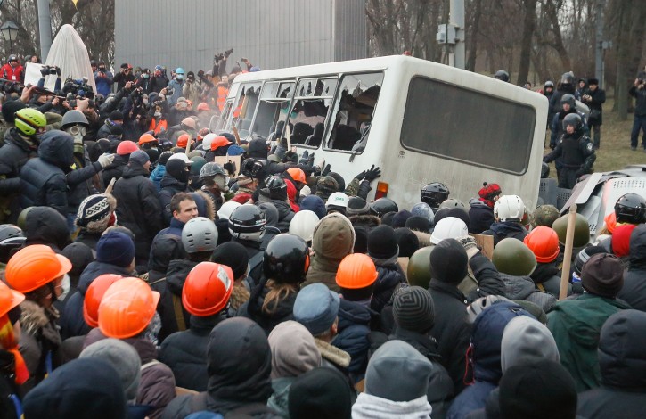 Protesters try to turn over a police bus as they clash with riot police during a protest in downtown Kiev, Ukraine, 19 January 2014. Violence broke out 19 January at anti-government protests as hundreds of opposition supporters armed with clubs tried to break through a police blockade and storm the Ukrainian parliament. The demonstrations took on a sharper tone after last week's passage of new laws that protesters and human rights groups said are designed to stifle dissent. They criminalize libel, establish new penalties for unlawful protests and make it easier to strip legislators of their immunity.  EPA/SERGEY DOLZHENKO