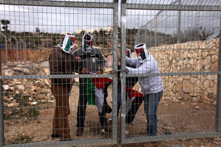Palestinian activists dismantling a gate in the Israeli security fence near the Jewish settlement of Efrat, near the West Bank town of Bethlehem, 26 January 2014.  The Palestinians took off the gate in order to reach Palestinian owned farmlands cut off by the barrier.  EPA/ABED AL HASHLAMOUN