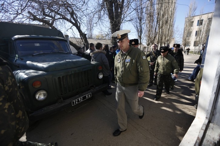 Ukrainian servicemen leave the Novofedorivka base after it was stormed, some 50 km (30 miles) west of Simferopol, Crimea, Saturday, March 22, 2014. On Saturday, a crowd stormed the Novofedorivka base, some 50 kilometers (30 miles) west of Simferopol, Ukraines Defense Ministry said. Ukrainian television station TSN said troops inside the base hoisted smoke grenades in an attempt to disperse groups of burly young men attempting to break through the front gates. TSN reported that there were children among the crowd attempting to seize the base. (AP Photo/Max Vetrov)